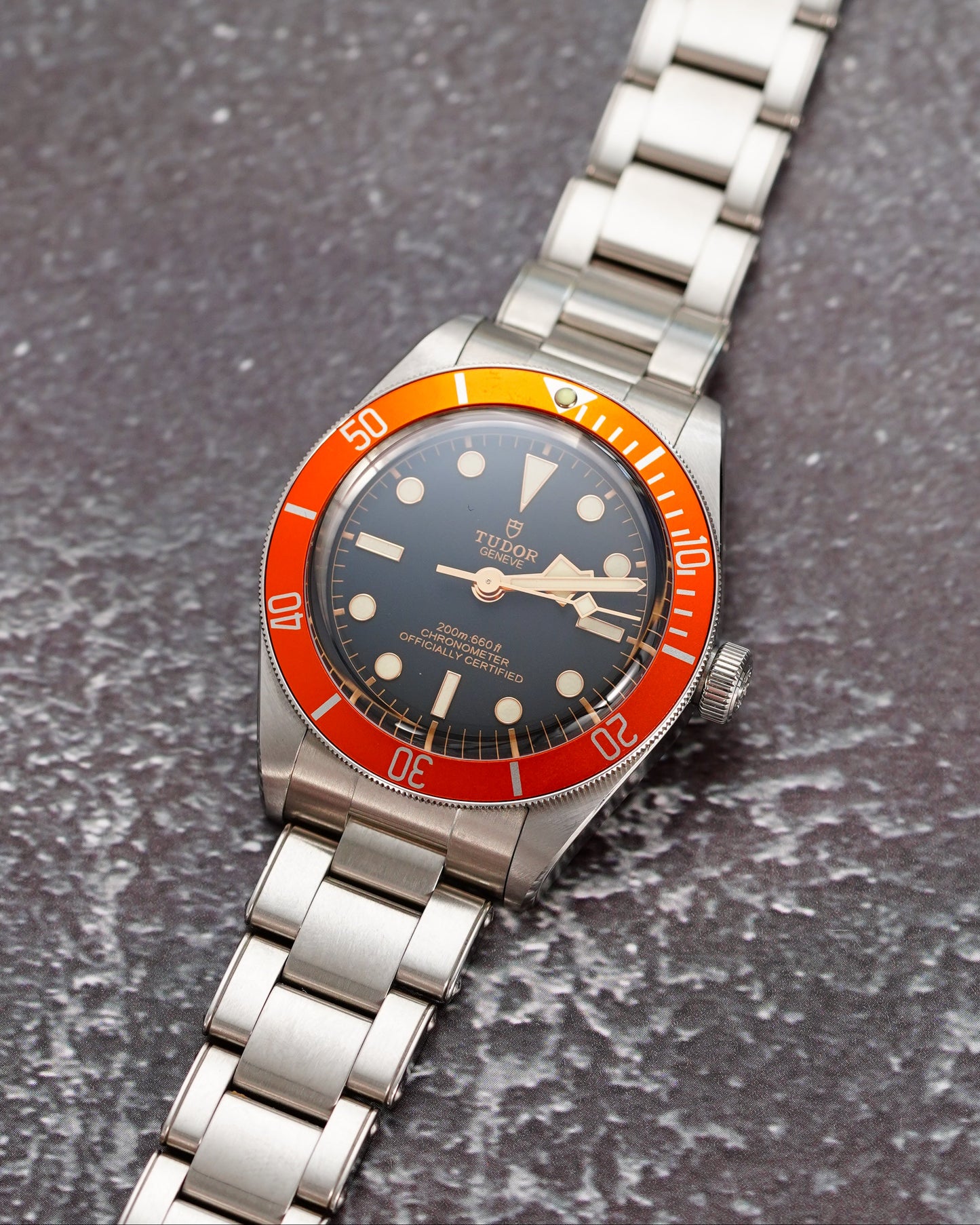 Silver wristwatch with a red and blue face on a textured gray surface