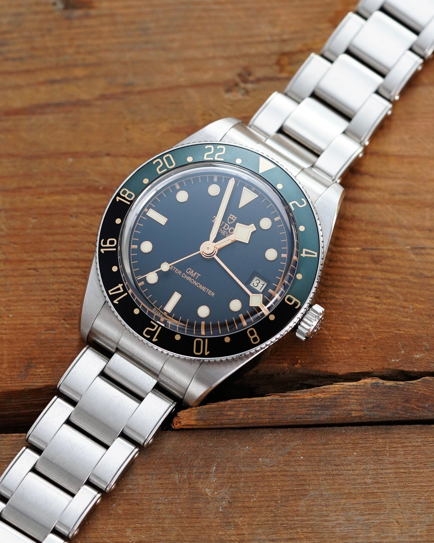 Silver wristwatch with a blue and black face on a wooden surface