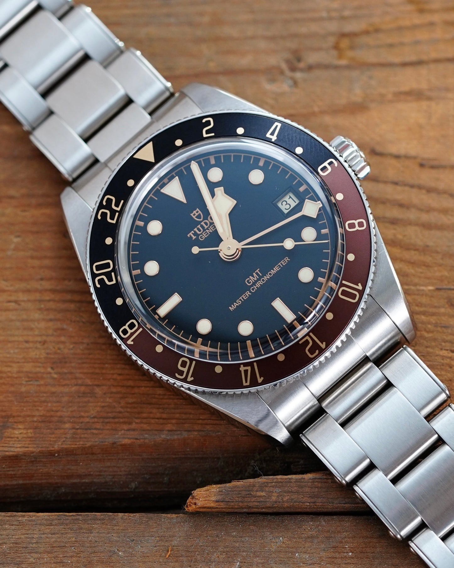 Silver watch with a blue and red face on a wooden surface