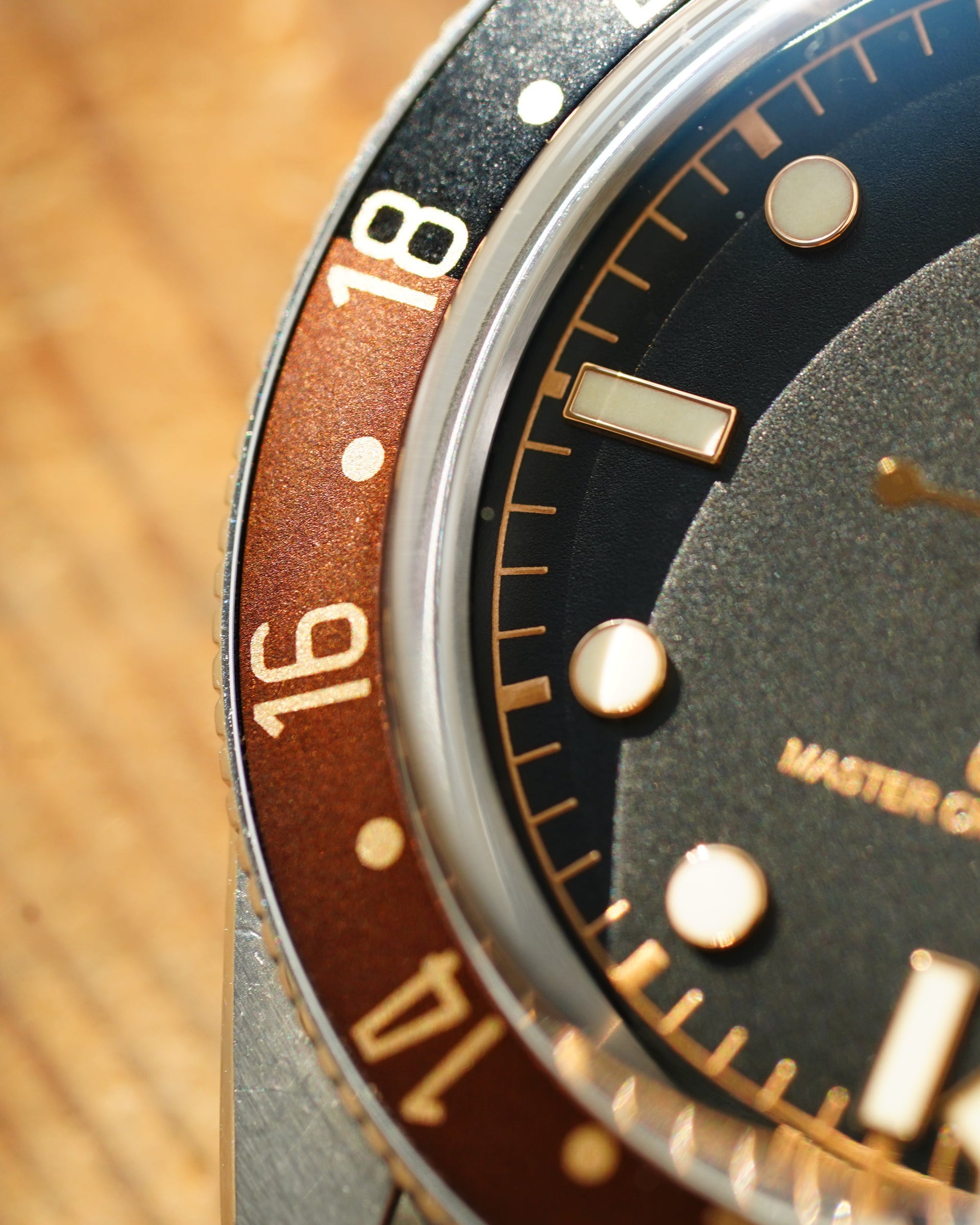 Close-up of a Tudor watch with a dark face and brown bezel.