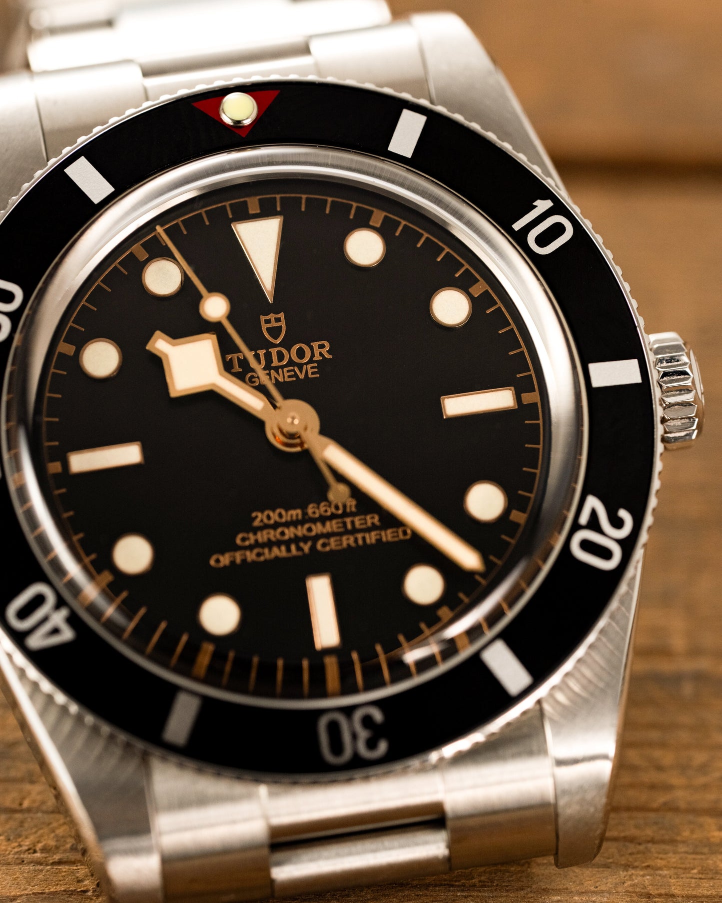 Tudor watch with black dial and silver case on a wooden surface
