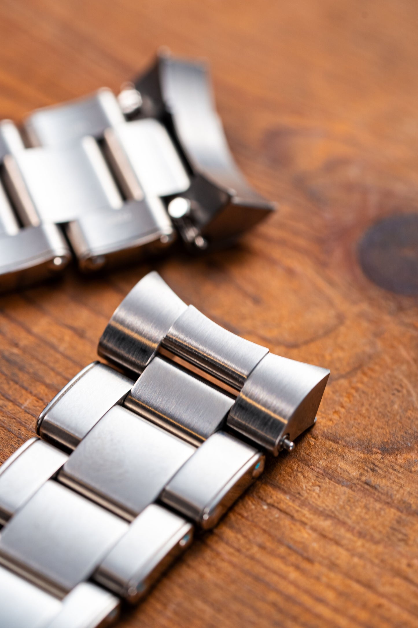 Close-up of a silver watch strap on a wooden surface
