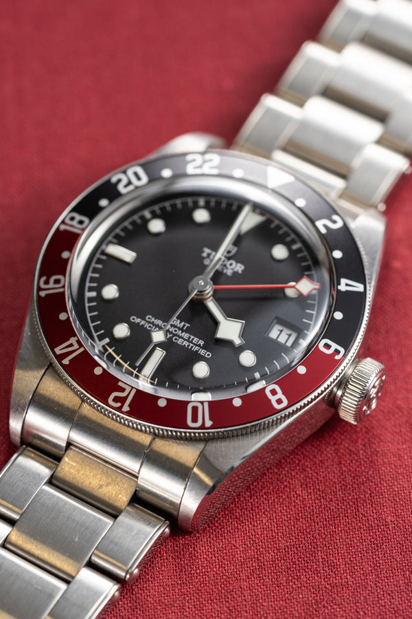 Silver watch with a black and red face on a red background
