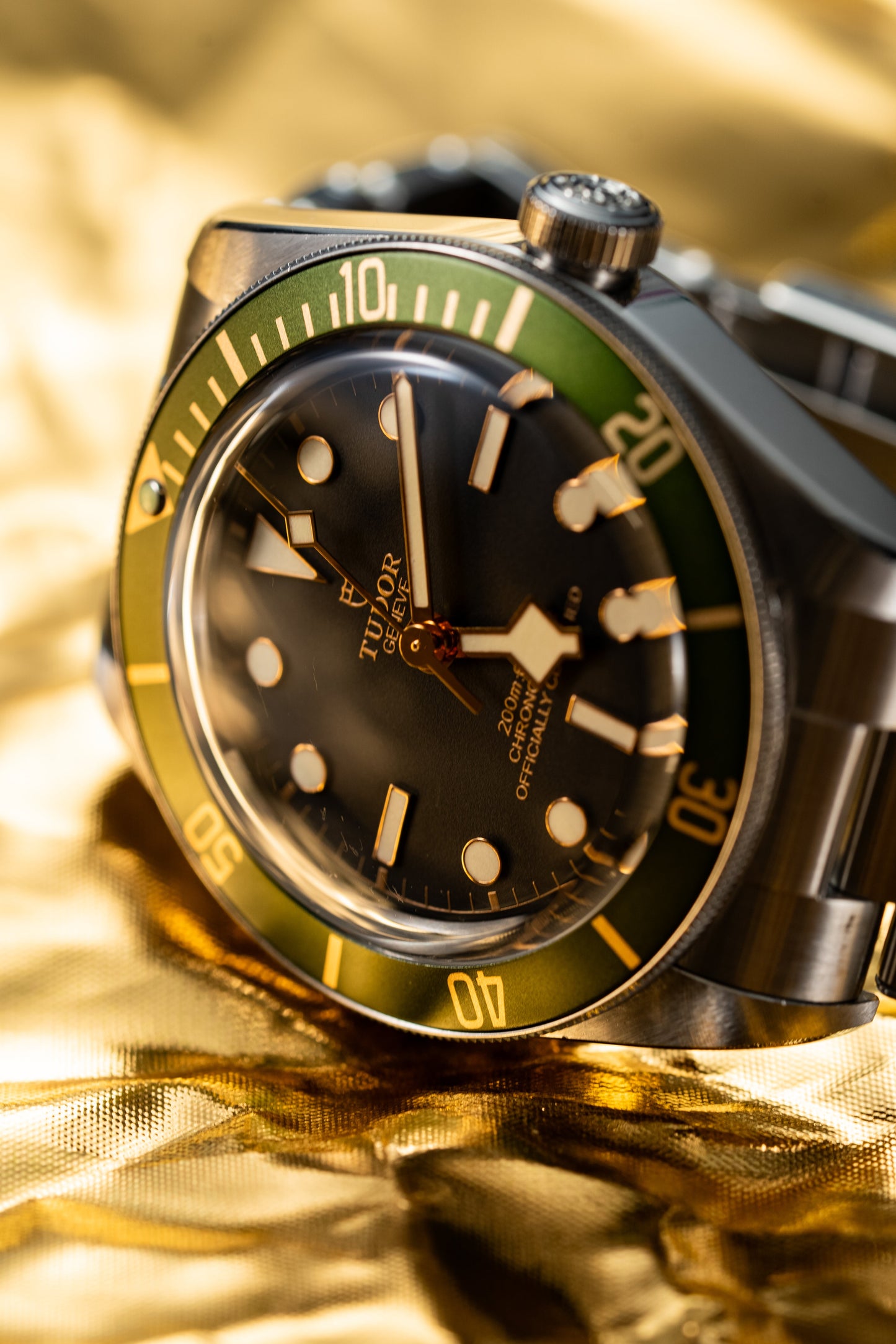 Luxury watch with black face and green bezel on a gold background
