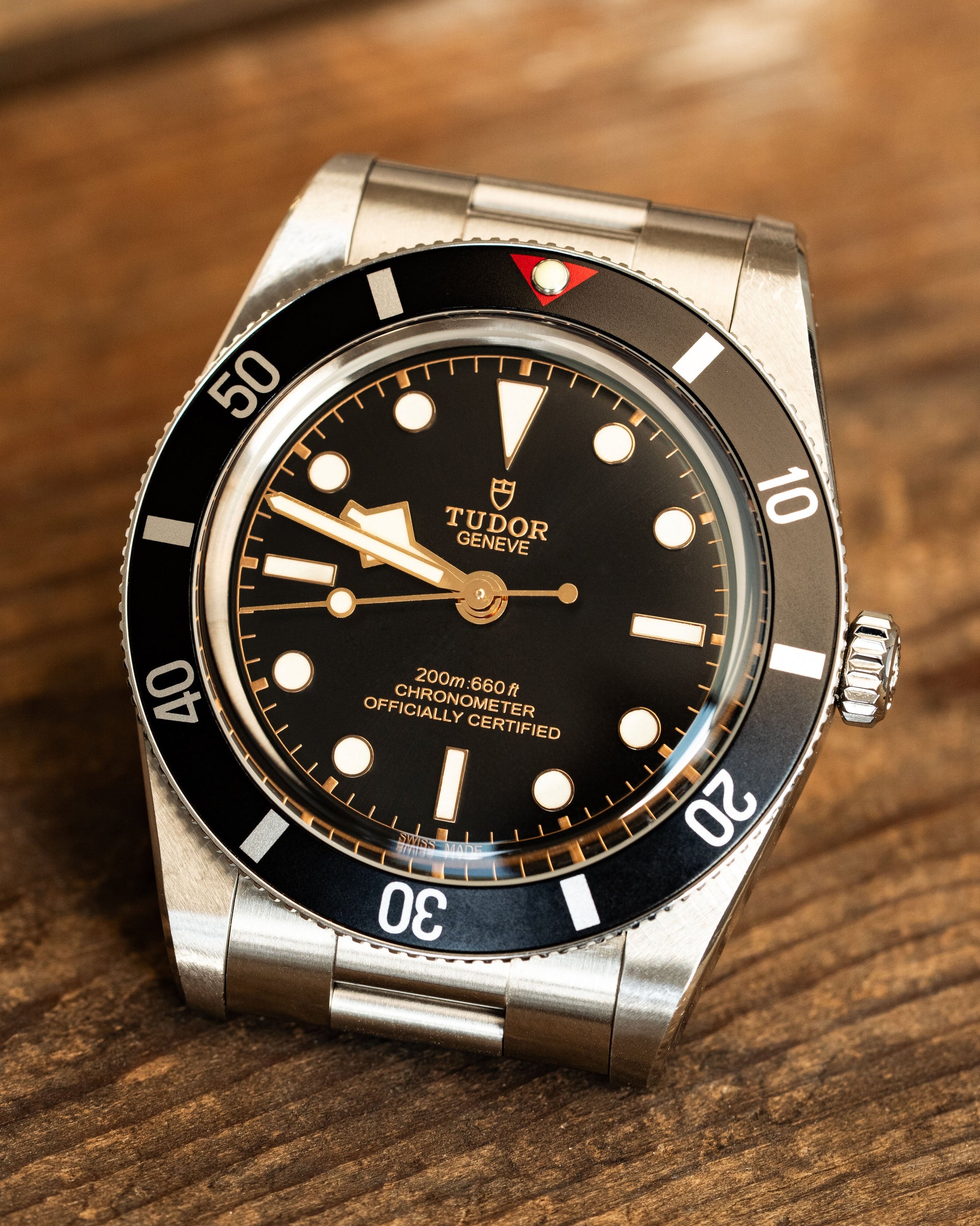 Tudor watch with black dial and silver case on a wooden surface